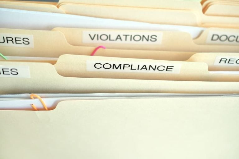 A bundle of files labelled with the words 'violations' and 'compliance'