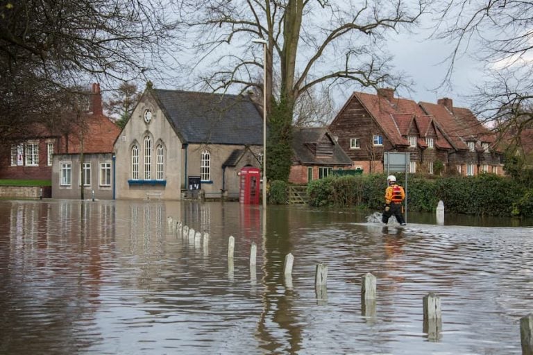 A flooded street with a man wading through the high waters