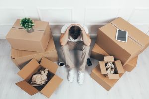A person sits surrounded by boxes looking stressed