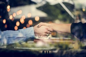 A close up of a handshake with dotted lights surrounding the hands