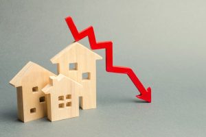 A 3d graphic of three small wooden model houses with a red arrow pointing downwards placed across the top
