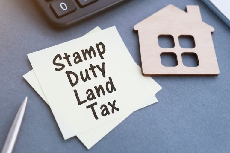 A computer keyboard with a post-it note next to it, bearing the words 'stamp duty land tax'