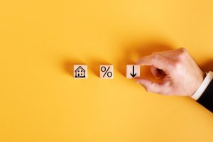 Three small wooden blocks, one with a picture of a house, one with a percent sign and one with a downward arrow