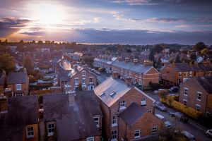 The sun breaks through clouds over rows of traditional English terraced houses