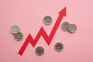 A red arrow points upwards surrounded by pound coins on a pink background