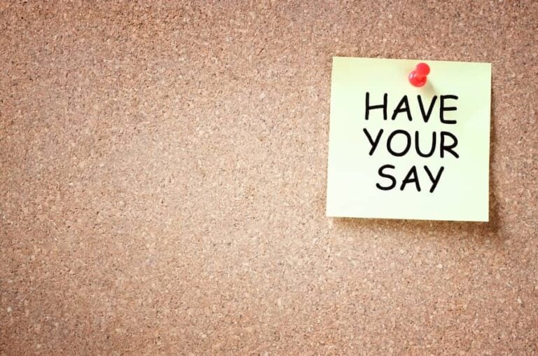 A yellow post-it with the words 'have your say' written on it, pinned to a cork board