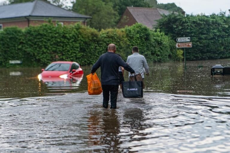 Men carrying belongings through a flooded street