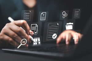 Hands on a laptop keyboard with a series of holographic documents floating above it