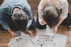 Aerial shot of a couple sitting on the floor looking at a pile of bills