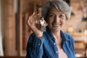 An older woman happily holding up a set of house keys