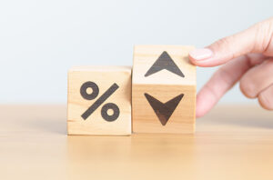 Two wooden blocks, one with a percentage sign and the other with up and down arrows. A hand holds the block with arrows so you can see both up and down