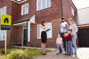 A family with young children being greeted by an estate agent outside a house for sale