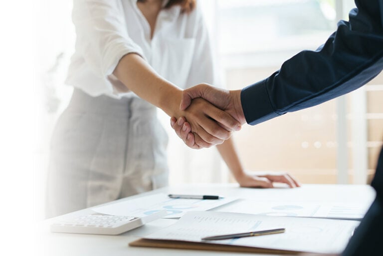 Close up of a handshake across a desk