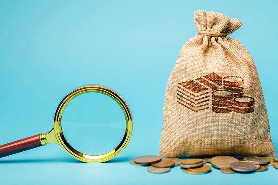 A bag of money next to a magnifying glass