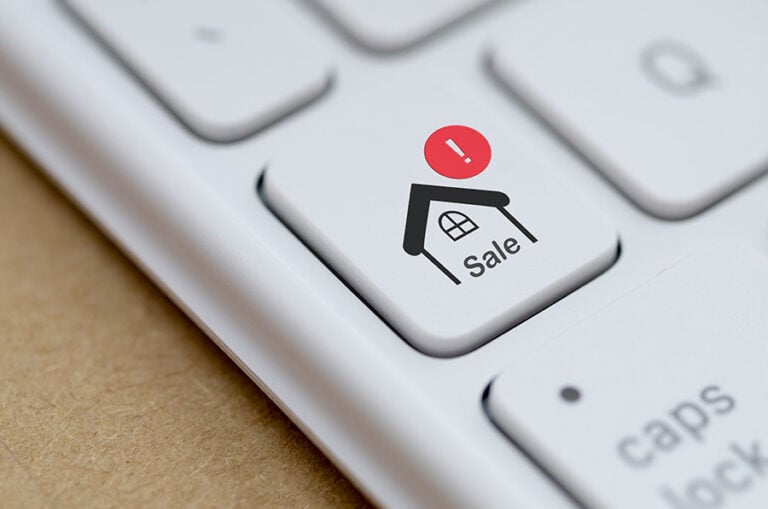 A computer keyboard with an image of a house and a red exclamation mark above it