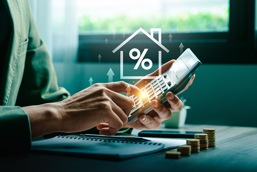 A hand hold a calculator, with an outline of a house and percentage sign laid over the photograph