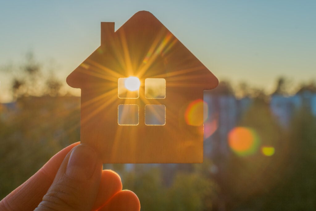 The shape of a house being held up in front of the sun, with the light shining through the windows