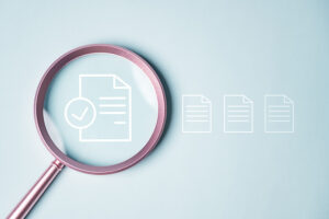 A magnifying glass laid over a white outline of a lined document, against a pale blue background