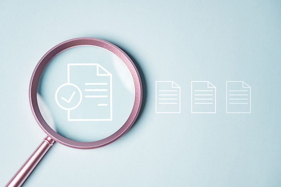 A magnifying glass laid over a white outline of a lined document, against a pale blue background