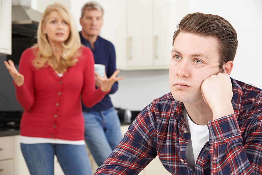 Mature parents look frustrated with an adult child sitting at the table