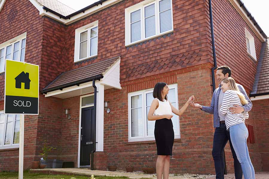 A young couple receive the keys to a large house from an estate agent