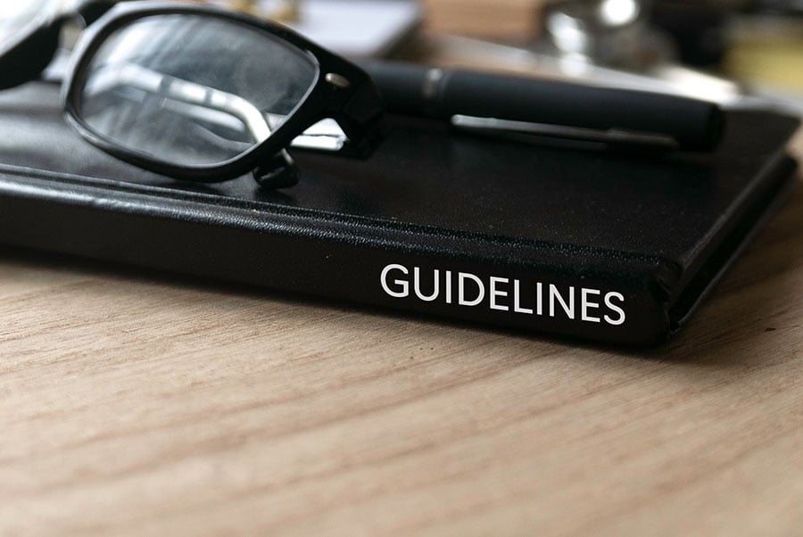 A black book on a desk with the word 'guidelines' printed on the spine in white