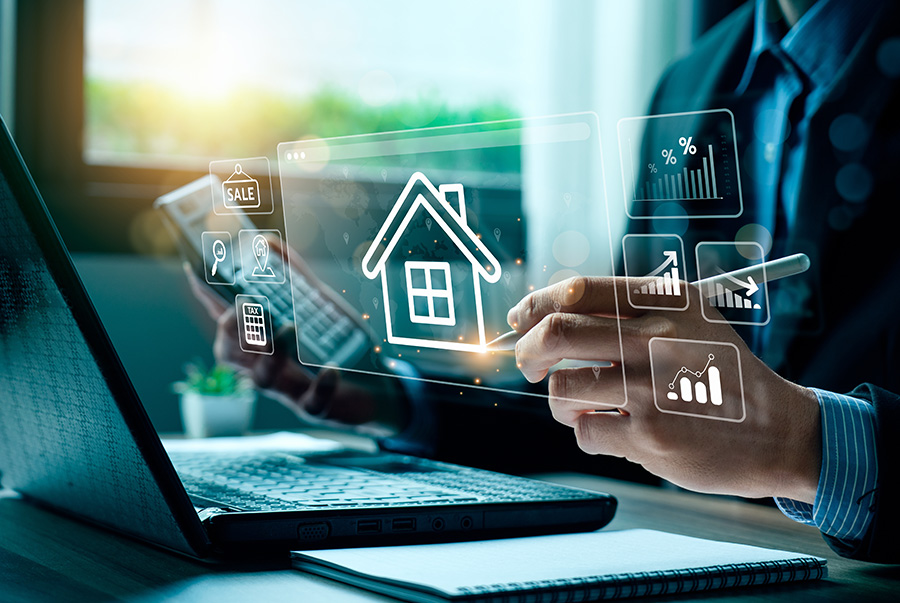 Graphics of a house and graphs laid over the image of a man holding a calculator and pen at an open laptop