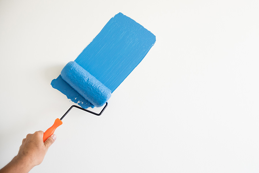 A roller of blue paint against a white background