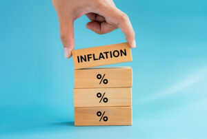 Four blocks, each with a % symbol on them, and a hand placing a block wit the word 'inflation' on the top