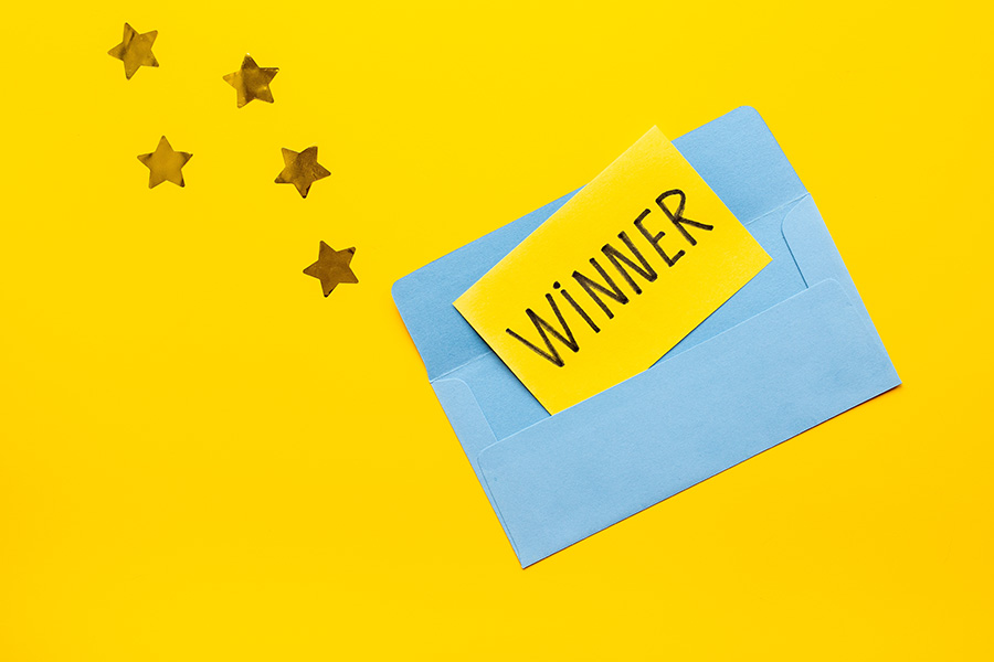 An open blue envelope with the word 'winner' written on a slip of paper inside