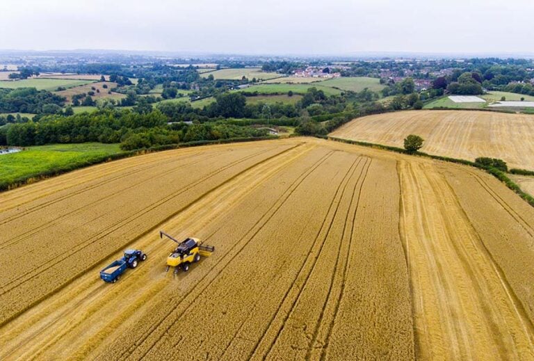 An aerial shot of a large area of agricultural land with two farm vehicles