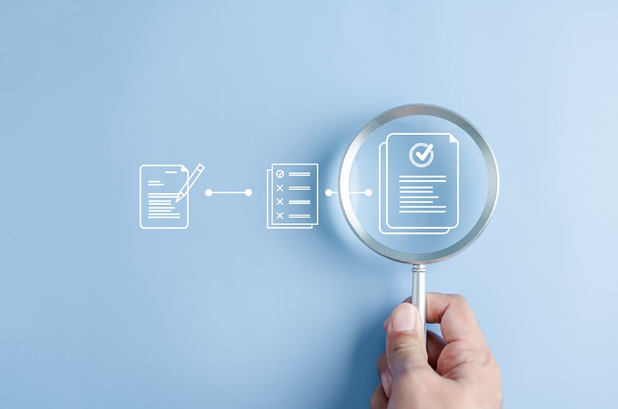 A magnifying glass held over graphics depicting lists on papers, some with ticks and some with crosses