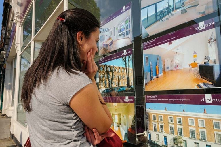 A young woman looking into an estate agent window