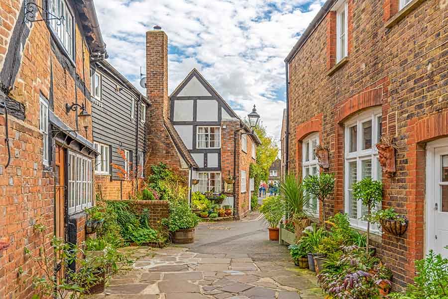 Houses on a cobbled street in Horsham, with lots of pots filled with plants and flowers