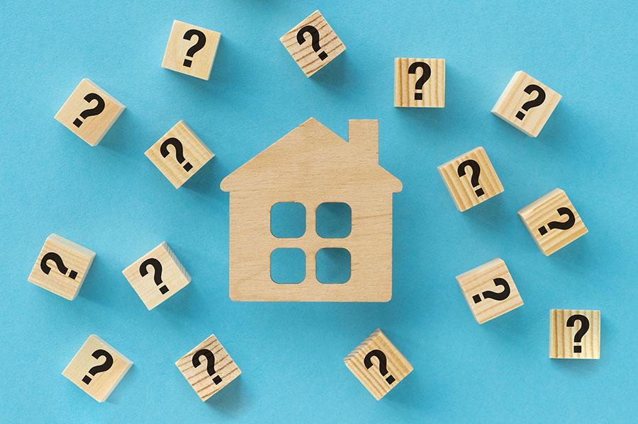 A small wooden house shape surrounded by question marks, against a blue background