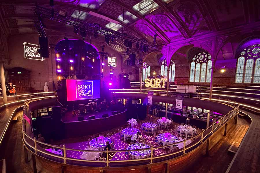 The venue for Sort Ball before the event, with dressed tables, coloured lights and branding