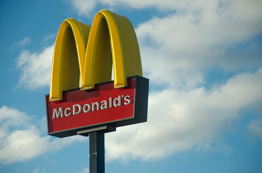 A McDonald's sign against a blue sky with white clouds