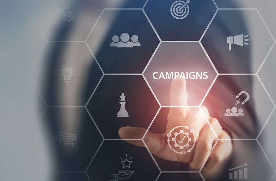 A blurred person in the background points to a graphic featuring the word 'campaign' and a grid including marketing-related symbols