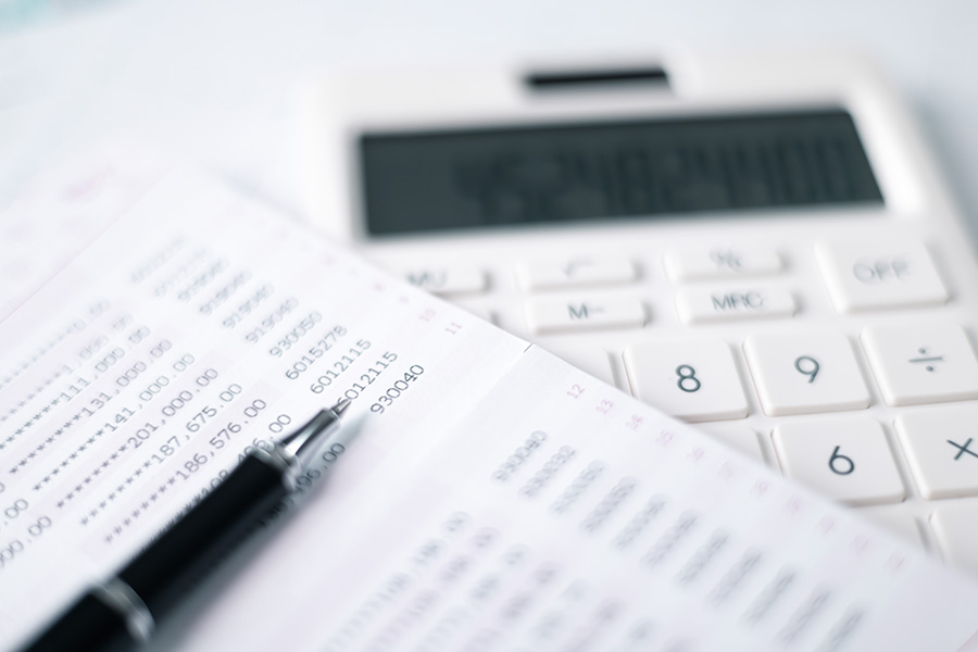 A print-out of account balances, next to a calculator and pen