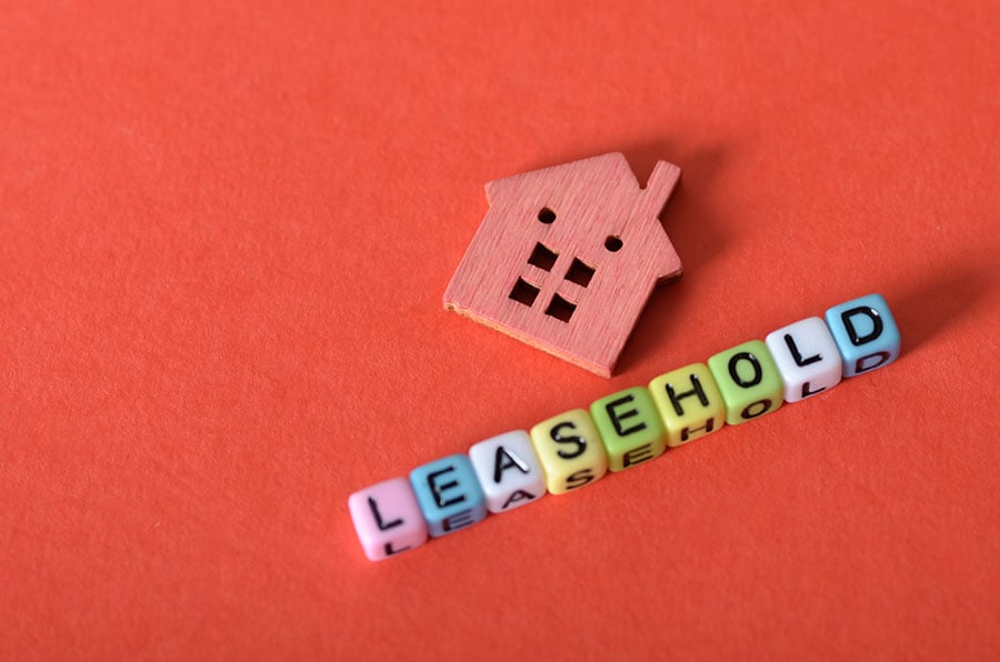 The word 'leasehold' spelled out on small coloured cubes, next to a small pink model house