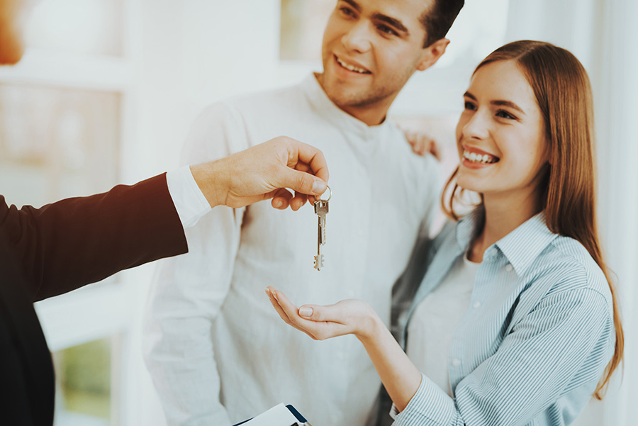 A smiling young couple are handed a set of house keys