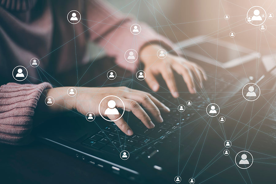Hands type on a laptop, overlaid with a graphic of connected basic people shapes