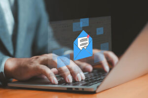 A graphic of a blue envelope is overlaid on a photo of hands typing on a laptop
