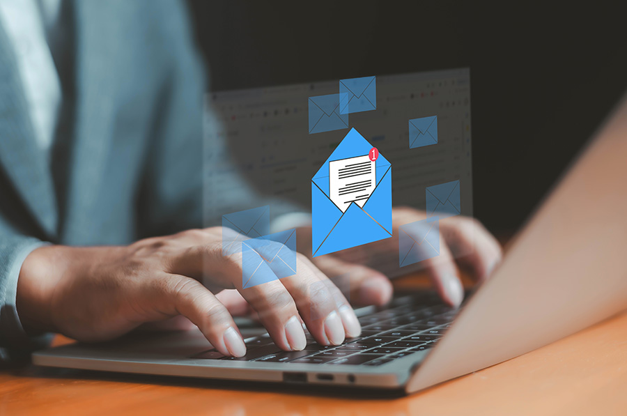 A graphic of a blue envelope is overlaid on a photo of hands typing on a laptop