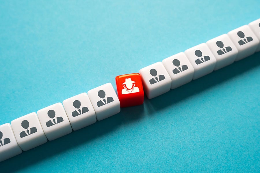 A line of cubes with the same outline of a person in black, with on red cube and a white outline of a person