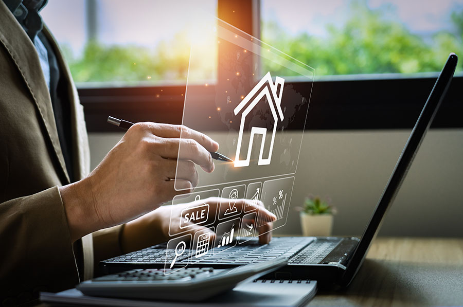 A close up of hands working on a laptop, with an overlaid graphic of a house and charts