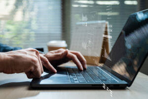 A close up of hands on a laptop keyboard overlaid with a graphic showing various types of data