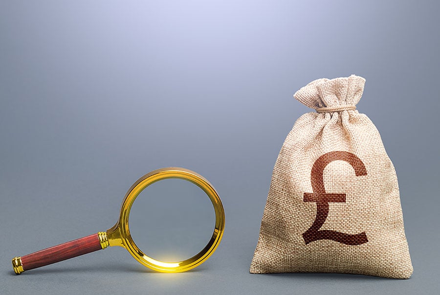 A sack of money with a pound sign printed on it, with a magnifying glass next to it