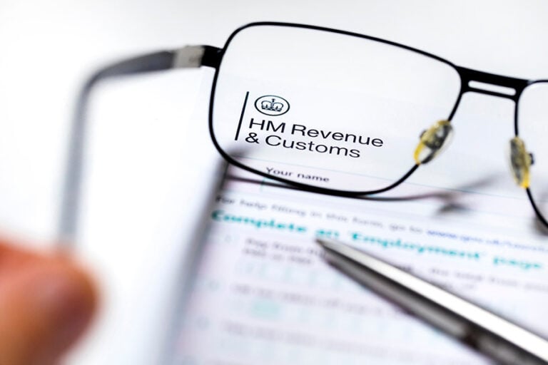 A form with the HMRC header, with a pair of reading glasses placed over it