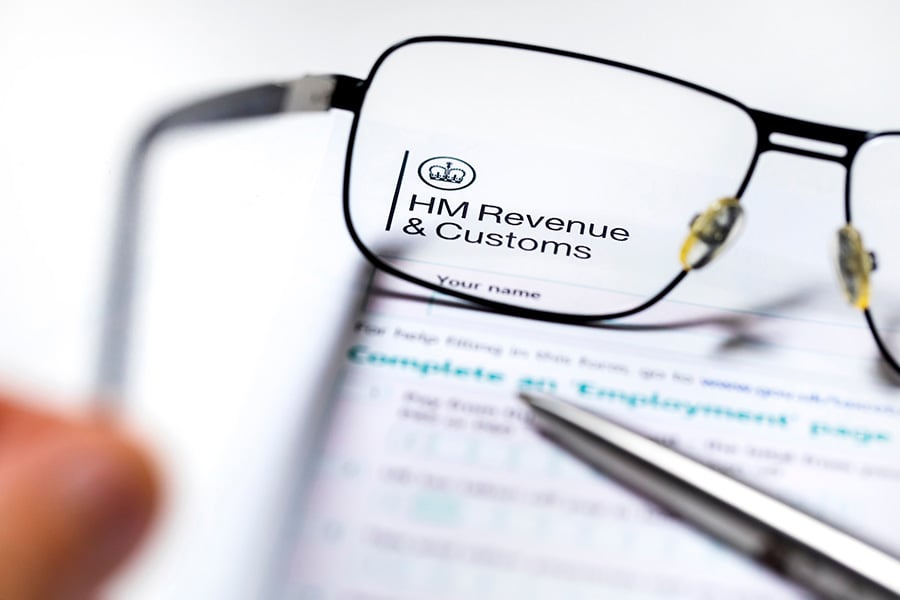A form with the HMRC header, with a pair of reading glasses placed over it